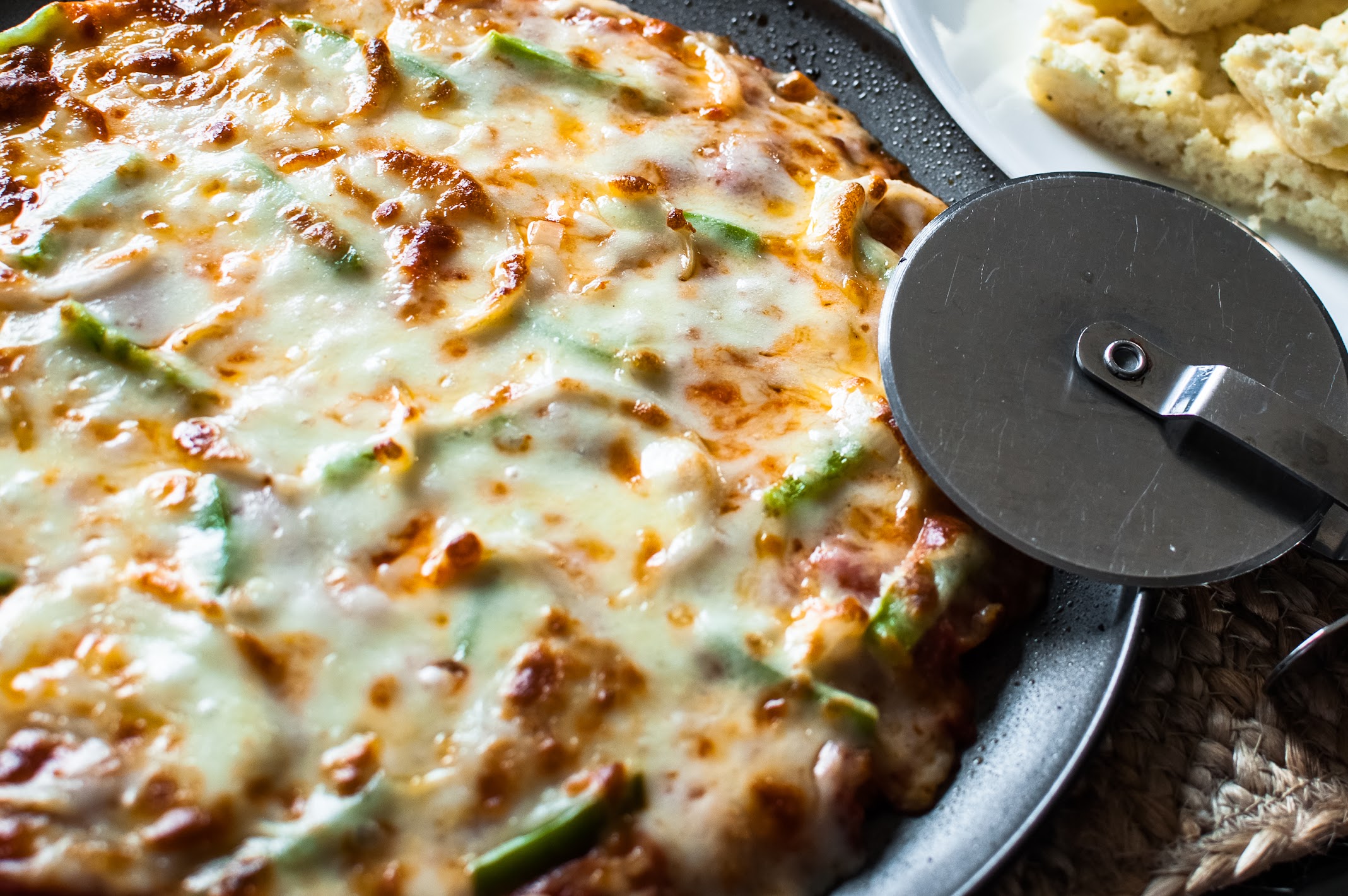 A gluten-free pizza with melted cheese and green peppers