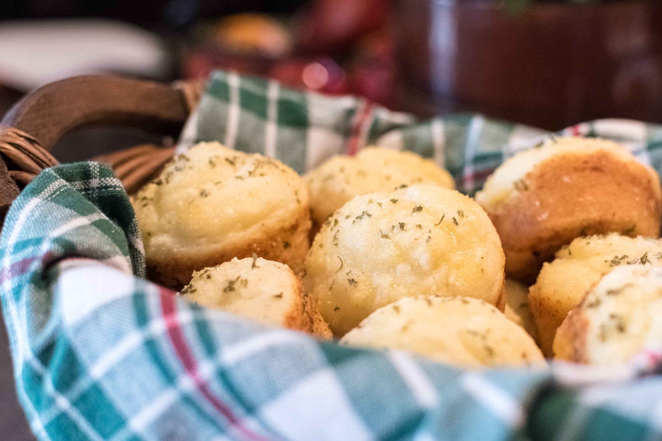 Parmesan dinner rolls in a basket lined with a plaid cloth